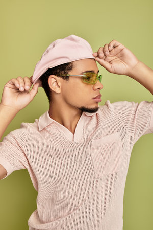 A stylish young african american man poses confidently against a vibrant green background.の写真素材