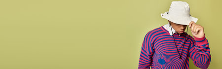 A stylish Black man poses confidently in a striped sweatshirt against a vibrant green background,...