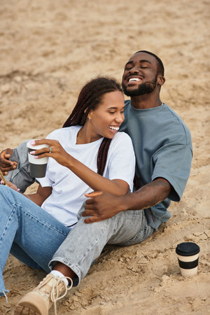 A young man and woman walk hand in hand, their faces lit up with joy and affection.