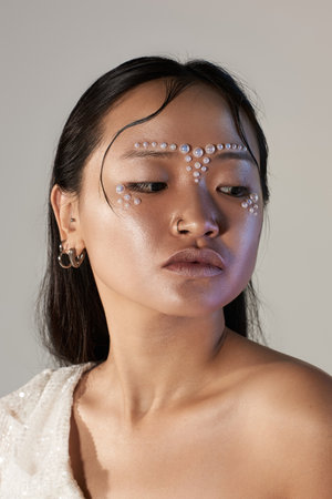 A young woman showcases innovative pearls on her face, highlighting her beauty and creativity.