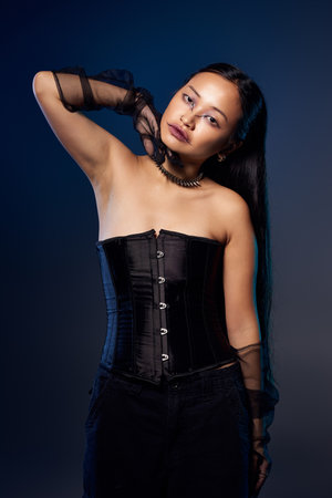 A young Asian woman showcases artistic makeup and a black corset in a dramatic, spooky atmosphere.の写真素材