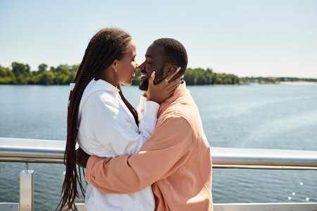 A joyful couple strolls along the waterfront, sharing tender moments and smiles under the sun.の写真素材