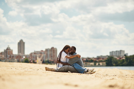 Young couple strolls hand in hand beside the water, embracing the warmth of love and nature.の写真素材