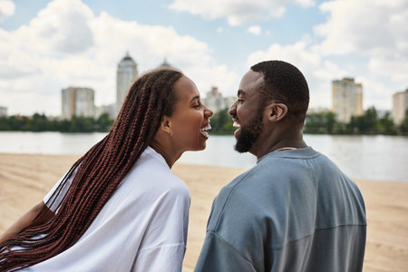Loving couple walks together on a riverside, sharing smiles and joy under a blue sky.の写真素材