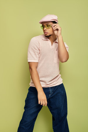 A fashionable young african american man poses confidently in a pink polo shirt with a flat cap.の写真素材