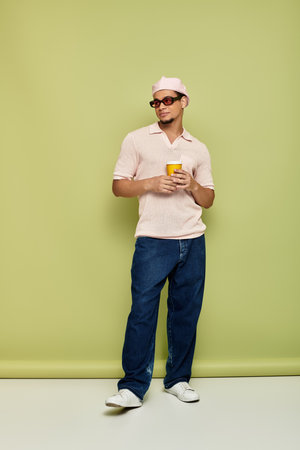 A stylish young Black man poses confidently with a drink in hand.