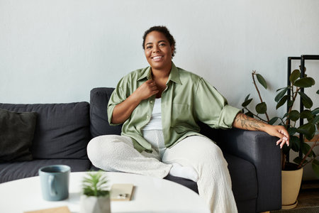 A joyful woman enjoys a peaceful moment at home, surrounded by modern decor and plants.の写真素材