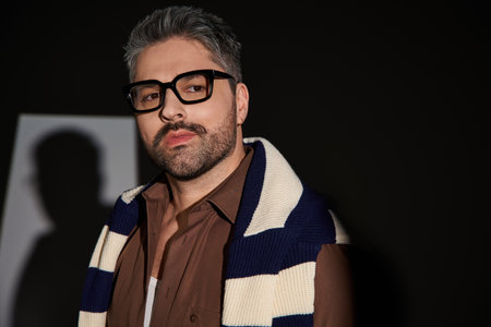A handsome man showcases his trendy outfit with glasses in an upscale studio environment.の写真素材