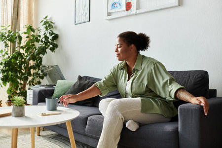 An African American woman enjoys her time at home, sipping tea and unwinding in comfort.の写真素材