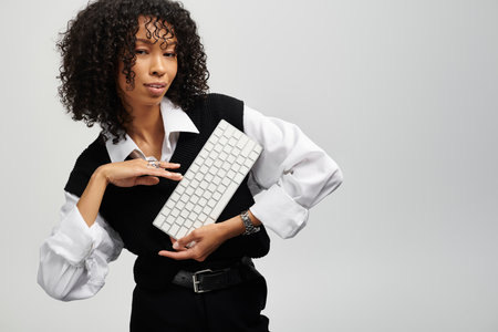 Woman in elegant business attire holds a keyboard, radiating professionalism.の写真素材