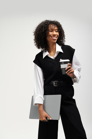 Confident young woman in stylish business attire enjoys coffee while preparing for work tasks.の写真素材