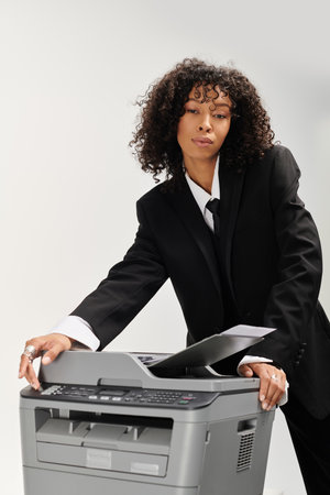 A young woman in sleek business attire operates a printer with elegance and confidence.の写真素材