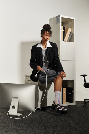 Dressed stylishly, the young woman elegantly connects equipment while seated.の写真素材