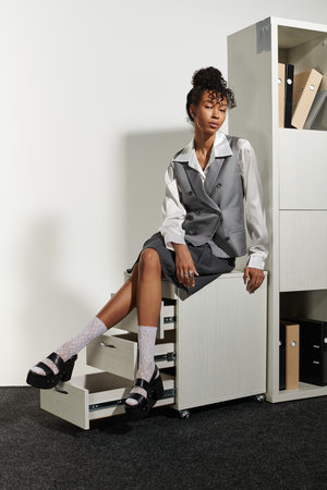 Young woman in elegant business attire sits confidently in a contemporary office space.の写真素材