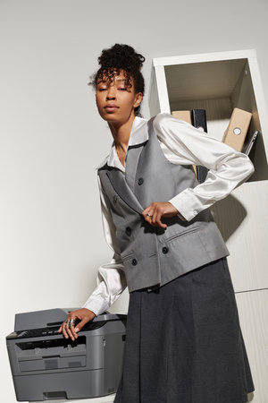 A young woman in stylish business attire poses confidently in an office, radiating professionalism.の写真素材