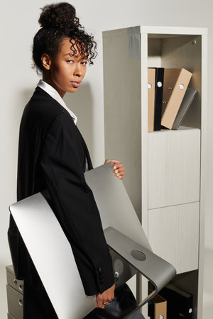 Young beautiful woman in business attire showcases an artsy workspace while holding a sleek item.の写真素材