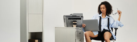 Young beautiful woman dressed elegantly in business attire engages with her laptop while seated.の写真素材