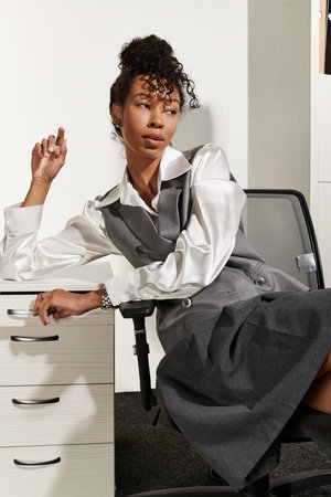 A young beautiful woman exudes elegance while seated in a modern office, showcasing her confidence.の写真素材