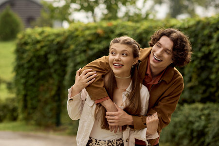 Young couple strolls hand in hand, sharing smiles and laughter in the sunny park.の写真素材
