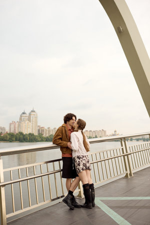 A young couple embraces happily while taking a walk on a scenic bridge near the water.の写真素材