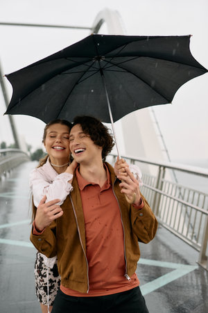 Loving couple shares laughter and warmth while walking together under a black umbrella in the rain.の写真素材