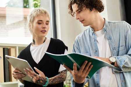 Two young individuals engage in productive discussion while reviewing documents in an office.