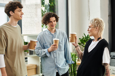 Three young professionals share ideas and laughter over coffee in a vibrant office environment.の写真素材
