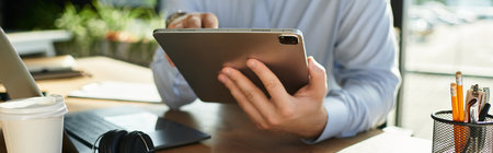 A young professional works diligently on a tablet, surrounded by a stylish office environment.