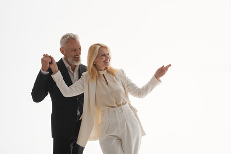 Loving couple dressed elegantly shares a joyful moment while dancing together in bright light.