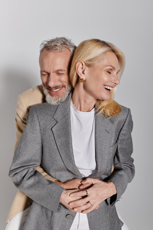 A loving senior couple embraces each other, radiating joy and affection while dressed fashionably.の写真素材