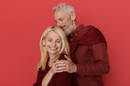 A senior couple embraces joyfully, dressed in fashionable outfits, radiating love and happiness.