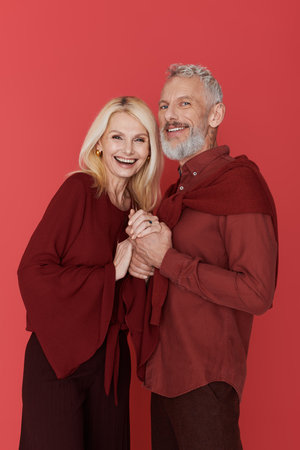 A loving senior couple joyfully holds hands, radiating happiness while dressed in trendy outfits.の写真素材