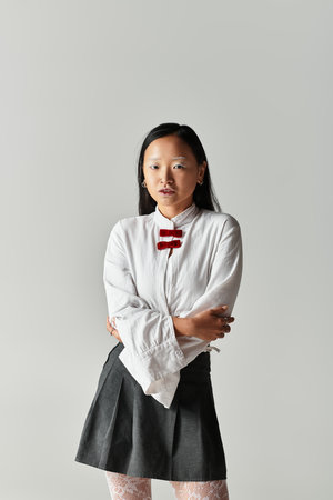 A young woman with blue hair poses confidently in a stylish outfit against a grey backdrop.の写真素材