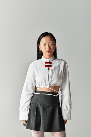 A pretty young woman with blue hair showcases a fashionable outfit in a minimalistic studio.