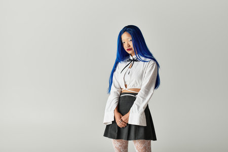 A pretty young Asian woman stands confidently in a trendy outfit with striking blue hair.の写真素材
