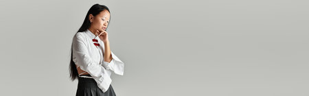 A young woman with blue hair models a chic outfit, exuding confidence in a minimalistic grey studio, bannerの写真素材