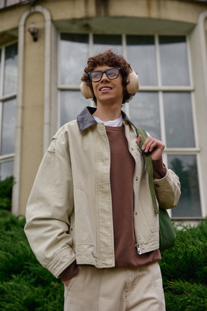 Handsome student strolls with joy, embracing the fresh air and atmosphere around campus.