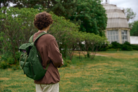 A handsome student strolls through serene greenery, appreciating the fresh air and tranquility.