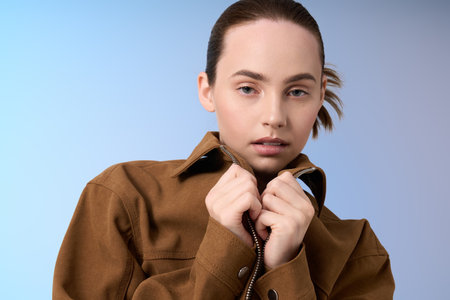 A fashionable young woman exudes confidence as she poses stylishly while adjusting her jacket.