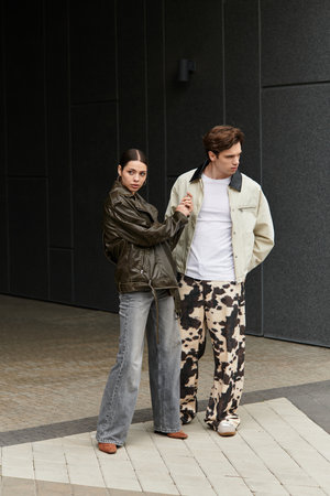 In a trendy urban location, a young couple shares a lighthearted moment, showcasing their affection.