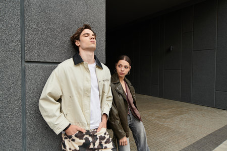 Joyful couple enjoys each others presence while leaning against a textured wall in the city.