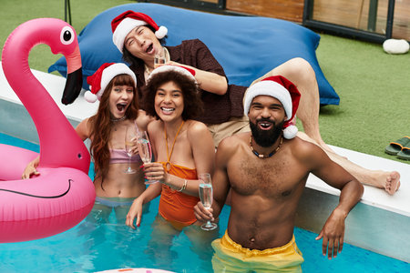 Stylish young friends enjoy a lively Christmas celebration by the pool, embracing happiness.