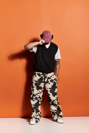 A young, stylish man expresses his individuality wearing eye catching attire, posing confidently.