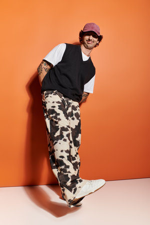 A stylish young man confidently poses in trendy attire, highlighting modern fashion choices.