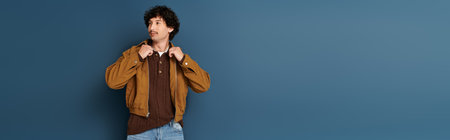 Handsome young man in a stylish outfit confidently adjusts his jacket, exuding charm and fashion.