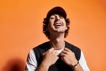 Handsome young man smiles broadly while displaying his trendy outfit and playful accessories.