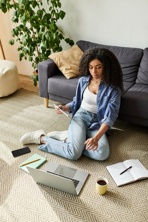 A focused African American woman engages in remote work from her modern, cozy home setup.