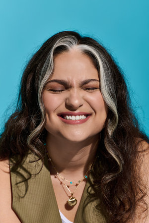 A beautiful woman with Waardenburg syndrome beams joyfully against a vivid blue backdrop.