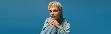 A confident young woman showcases her unique style against a calming blue backdrop.のeditorial素材