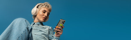 Young woman with trendy style listens to music on her phone, immersed in a blissful moment.のeditorial素材